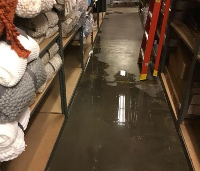 Wet flooring in a building with sales items on a shelf. 