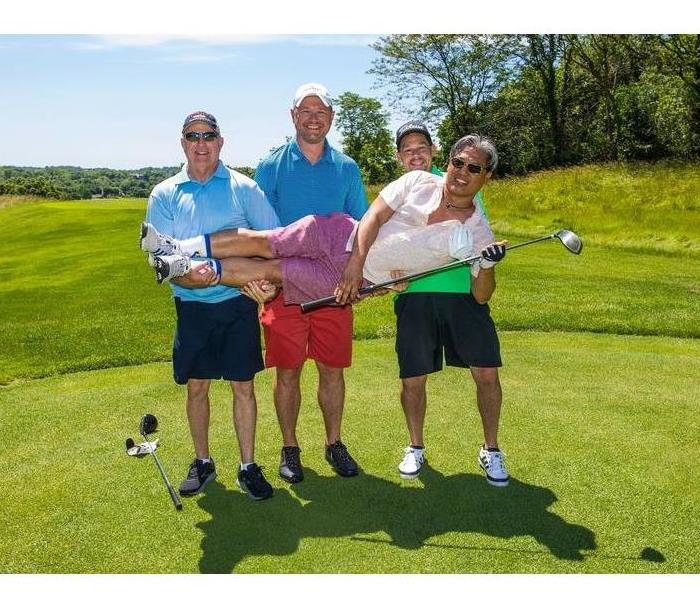 Four people posing on a golf course