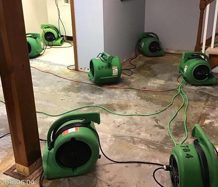 Flooring removed from a room with SERVPRO equipment on the floor. 